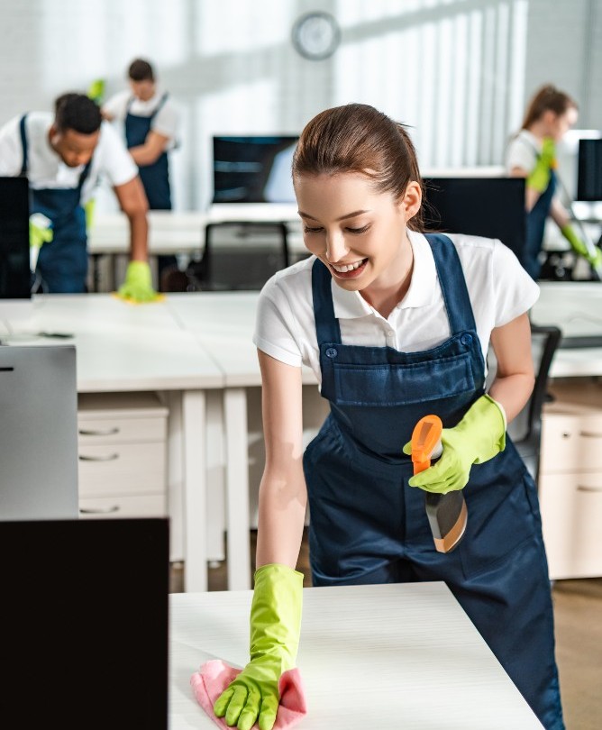 cheerful-cleaner-in-overalls-cleaning-office-desk-2022-01-18-23-41-03-utc